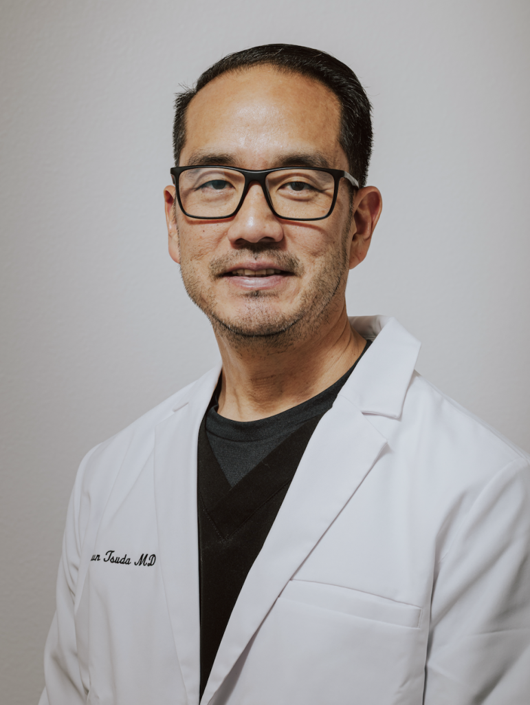 Man in white coat smiling in a headshot